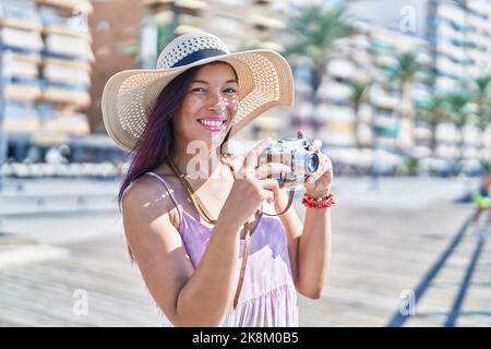 Young beautiful hispanic woman tourist using vintage camera at street Stock Photo