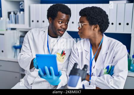 African american man and woman scientists using touchpad working at laboratory Stock Photo