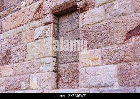 Bricked up window of an old ancient building with uneven stone wall close-up Stock Photo