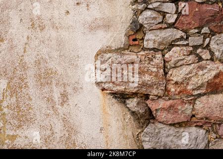 Ragged joint of an old stone wall with a cement plastered grunge surface. Copy space. Stock Photo