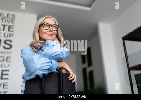 portrait of a successful business woman sitting on a chair backwards in a modern office. Business Invoice Tax Management concept Stock Photo