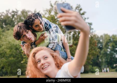 Best friends taking selfie having fun together outdoor, enjoying carefree lifestyle. Multiethnic friendship. Modern technology. Stock Photo