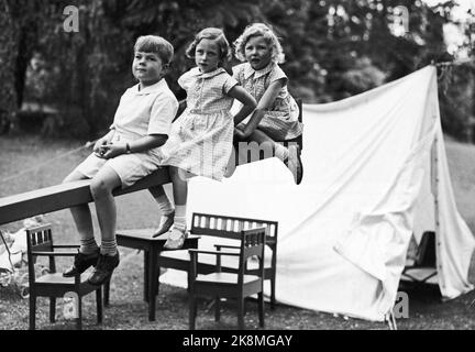 Skaugum June 1937. Princess Ragnhild (in the middle) and Princess Astrid play in the garden at Skaugum, along with an unidentified boy. The three together, sitting on a domp hined in the garden. A white tent in the background. Photo: NTB / NTB Stock Photo
