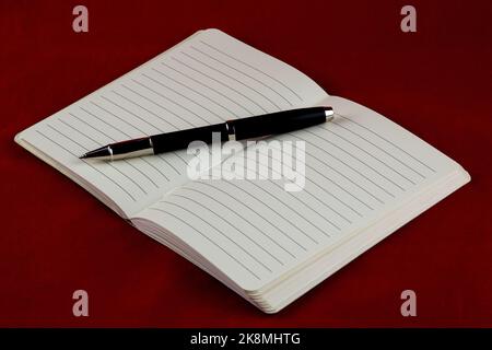 Rollerball pen and open notebook on a red table cloth Stock Photo