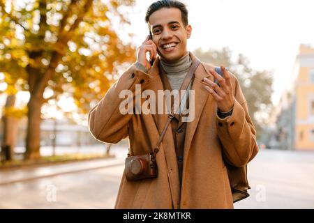 Young man gesturing while talking on mobile phone in park outdoors Stock Photo