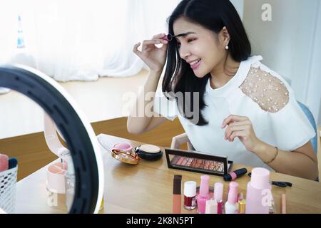 online trading business, a beautiful young woman working independently at home reviewing cosmetic products through the camera to customers to increase Stock Photo