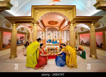 Hindu devotees pray at the Veda Mandir Hindu temple in Bolton during the Diwali, the mid-autumn Festival of Lights, that is a celebration of light over darkness, and good over evil. Picture date: Monday October 24, 2022. Hindus, Jains and Sikhs come together with their families in a vibrant, colourful salute lasting five days. Associated mainly with Lakshmi, the goddess of prosperity, and Ganesha, the god of wisdom. Stock Photo