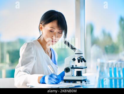 Scientist researcher working writing down analysis information at modern medical research laboratory. Medicine, biotechnology, microbiology concept Stock Photo