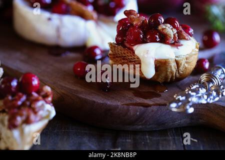 Toasted bread served with baked Camembert Brie cheese and a cranberry, honey, balsamic vinegar and nut relish. Selective focus with extreme background Stock Photo