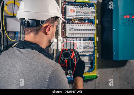 Man, an electrical technician working in a switchboard with fuses. Stock Photo