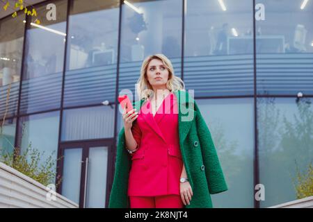Pensive thoughtful woman holding smartphone look away lost on sad thoughts waiting first step from man, call or text message or date invitation from b Stock Photo