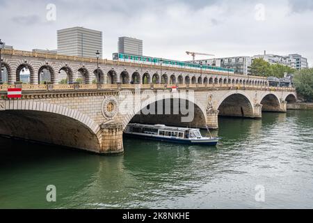 Pont de Bercy combined Road and Rail Bridge across River Seine with a train crossing and a boat emerging from under the bridge, Paris, France Stock Photo