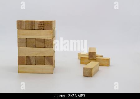 Tower wooden block, builds tower from wooden blocks against white background. The wooden bricks lying around randomly Stock Photo