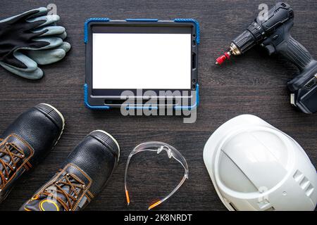 Digital tablet with layout and worker clothes, top view. Stock Photo