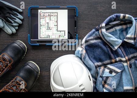 Digital tablet with layout and worker clothes, top view. Stock Photo