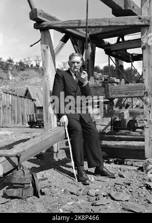 Røros 19490717 author Johan Falkberget, with the mine 'Christianus Sextus' in the background. The work in and around the mine formed the basis for many of his books. Falkberget with cane and pipe. Photo: NTB / NTB Stock Photo