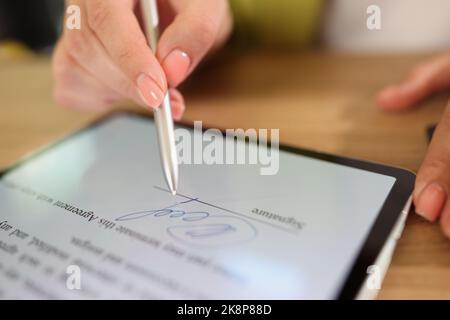 Female hand signing e-document on tablet with stylus Stock Photo