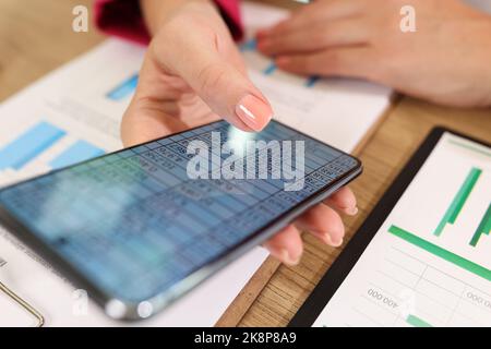 Female hands holding modern smartphone with stats data on screen Stock Photo