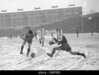 Oslo 19471115. Football in snowy weather at Bislett. The football match between Dynamo and Skeid was played on winter. Before and during the match it snowed tightly, and the grass mat was white and hard. 32,000 spectators are a record at Bislett. Here we see Skeid's keeper springs towards 'Dynamos' Sergei Solovev, which has all lifted the leg to a power kick. Photo: Current / NTB Stock Photo