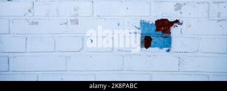 Old brick wall painted white with blue and red geometric squares. Stock Photo