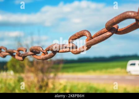 Old rusty chain on the field on background of the sky Stock Photo