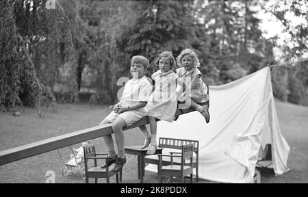 Skaugum June 1937. Princess Ragnhild (in the middle) and Princess Astrid play in the garden at Skaugum, along with an unidentified boy. The three together, sitting on a domp hined in the garden. A white tent in the background. Photo: NTB / NTB Stock Photo