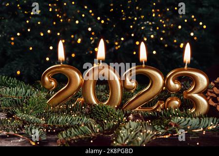 Holiday background Happy New Year 2023. Numbers of year 2023 made by gold burning candles on bokeh festive sparkling background. celebrating New Year Stock Photo