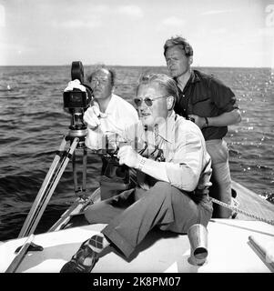 Hankø in the summer of 1956. Recording Norway's first feature film in color, titled 'Smugglers in tuxedo'. Here, photographer Finn Bergan has lined up the camera on board a sailboat. In front, producer Per G. Jonson/Per Gunnar 'Pege' Jonson (script, film photographer, clipper) is intensely included in the customs cruiser's hunt for the smugglers. Photo: Aage Storløkken / Current / NTB. Stock Photo