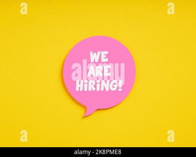 The message we are hiring on pink speech bubble on yellow background. Business career recruitment, vacant job position and employment announcement. Stock Photo