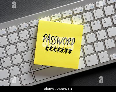 The word password written on a sticky note paper on computer keyboard. Password management or internet cyber security concept. Stock Photo