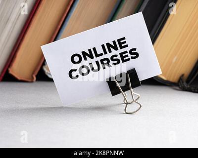 The message online courses written on a business card with books background. Online education training concept. Stock Photo