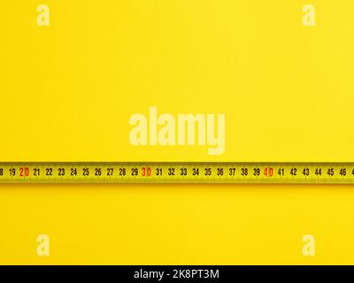 To evaluate or measure the size concept. Tape measure on yellow background with copy space. Stock Photo