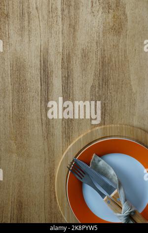 Empty plate with cutlery on rustic empty table, copy space, rim on plate - orange color Thanksgiving. Stock Photo