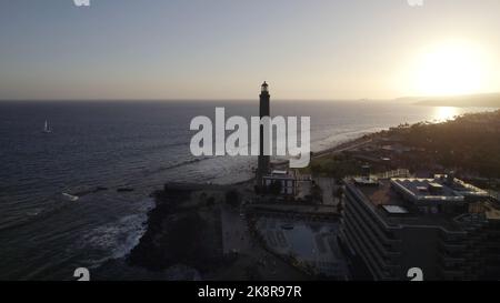 A drone shot of the Maspalomas Lighthouse near the beach during sunset in Gran Canaria, Spain Stock Photo