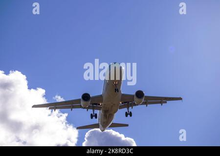 A big white airplane flying in the blue sky with many white and dark blue clouds Stock Photo