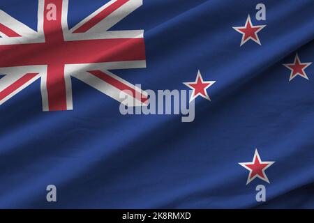 New Zealand flag with big folds waving close up under the studio light indoors. The official symbols and colors in fabric banner Stock Photo