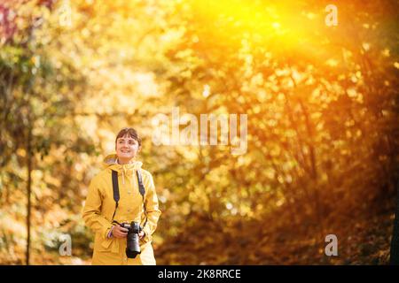 Tourist Woman Walking And Taking Photos In Forest. Lady Photographed Nature. Young Pretty Caucasian Happy Smiling Girl Woman On Road In Autumn Forest Stock Photo