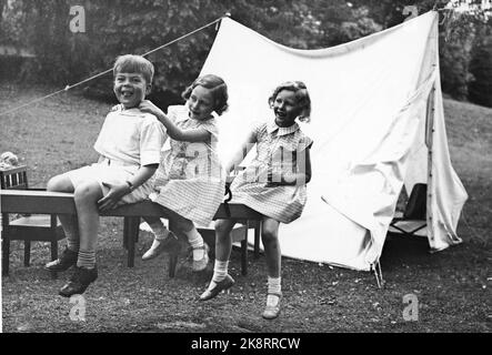 Skaugum June 1937. Princess Ragnhild (in the middle) and Princess Astrid play in the garden at Skaugum, along with an unidentified boy. The three together, sitting on a domp hined in the garden. A white tent in the background. Photo: NTB / NTB Stock Photo
