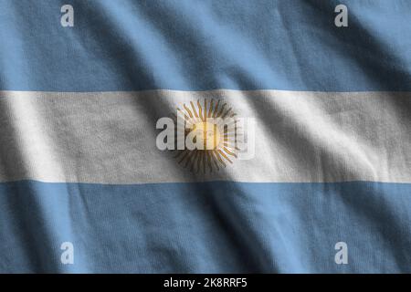 Argentina flag with big folds waving close up under the studio light indoors. The official symbols and colors in fabric banner Stock Photo