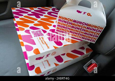 Cartons of Dunkin' donuts and Munchkin donut holes on the front passenger seat of a vehicle. Stock Photo