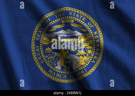 Nebraska US state flag with big folds waving close up under the studio light indoors. The official symbols and colors in fabric banner Stock Photo