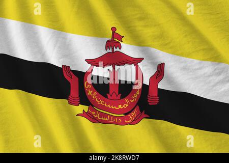 Brunei Darussalam flag with big folds waving close up under the studio light indoors. The official symbols and colors in fabric banner Stock Photo