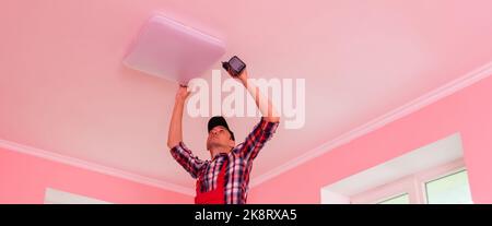An electrician installs a chandelier on the ceiling. Hands of an electrician installing and connecting a lamp to a ceiling. Stock Photo