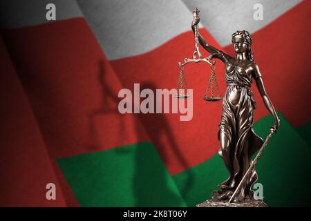 Oman flag with statue of lady justice and judicial scales in dark room. Concept of judgement and punishment, background for jury topics Stock Photo
