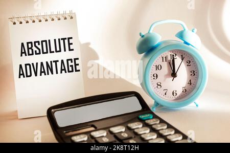 ABSOLUTE ADVANTAGE text in notepad on white background with calculator and clock Stock Photo