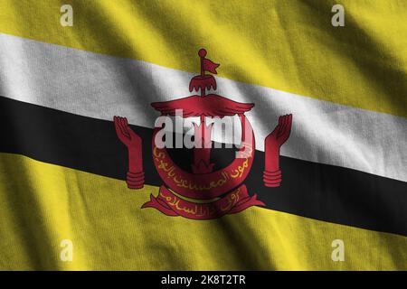 Brunei Darussalam flag with big folds waving close up under the studio light indoors. The official symbols and colors in fabric banner Stock Photo