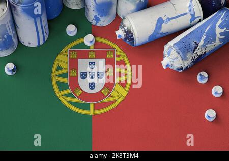 Portugal flag and few used aerosol spray cans for graffiti painting. Street art culture concept, vandalism problems Stock Photo