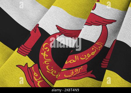 Brunei Darussalam flag with big folds waving close up under the studio light indoors. The official symbols and colors in fabric banner Stock Photo