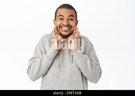 Portrait of hopeful arab guy praying, making wish and holds fingers crossed for good luck, anticipating, standing over white background Stock Photo