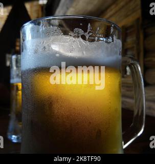 Glasses of frothy craft beer in a beer mugs on wooden table at old pub Stock Photo